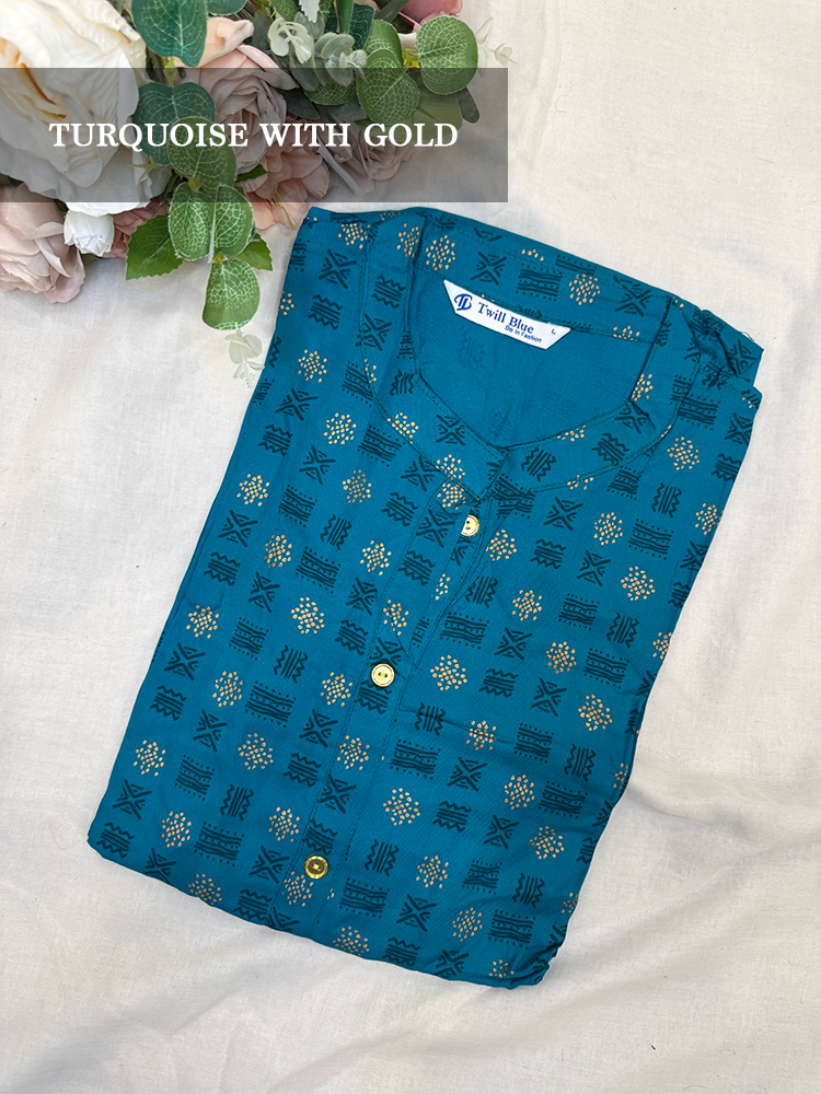 Folded blue kurti with gold patterns on a white surface with flowers in the background