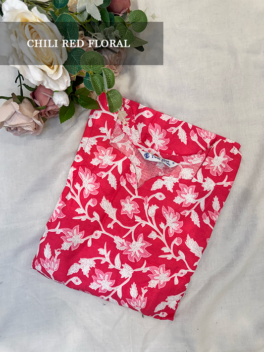Red floral kurti on a white fabric background with flowers on top
